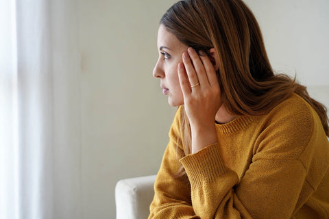 ad-woman-looking-anxiously-out-window-while-sitting-on-chair