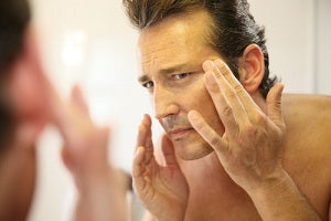 Middle-aged man in bathroom applying facial lotion