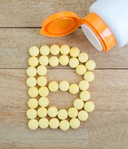 Yellow pills forming shape to B alphabet on wood background