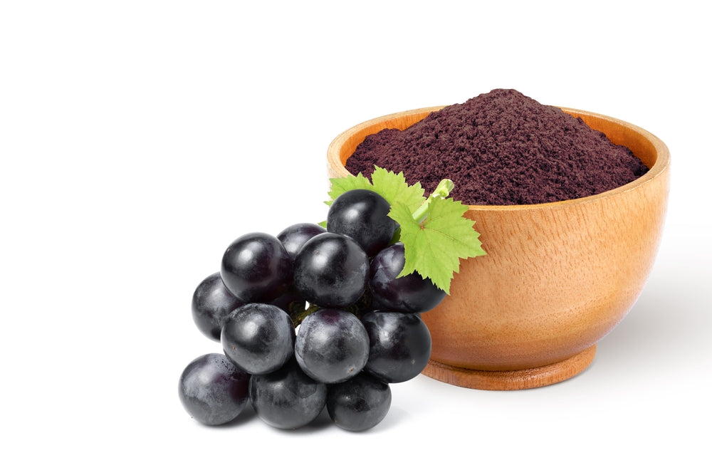 Bunch-of-purple-grapes-beside-wooden-bowl-of-grape-extract-powder