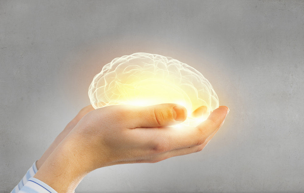 Person holding glowing brain in their hands