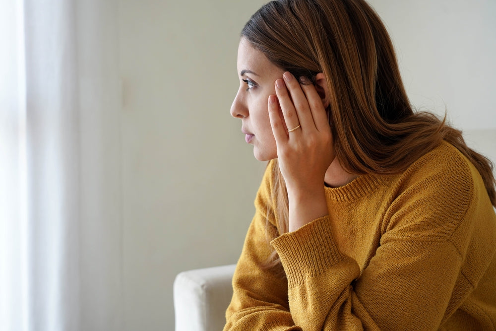 ad-woman-looking-anxiously-out-window-while-sitting-on-chair
