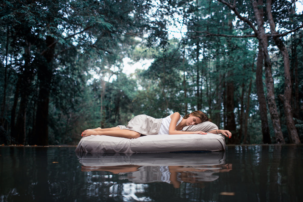 Woman-sleeping-peacefully-on-air-mattress-floating-on-pond-in-forest.