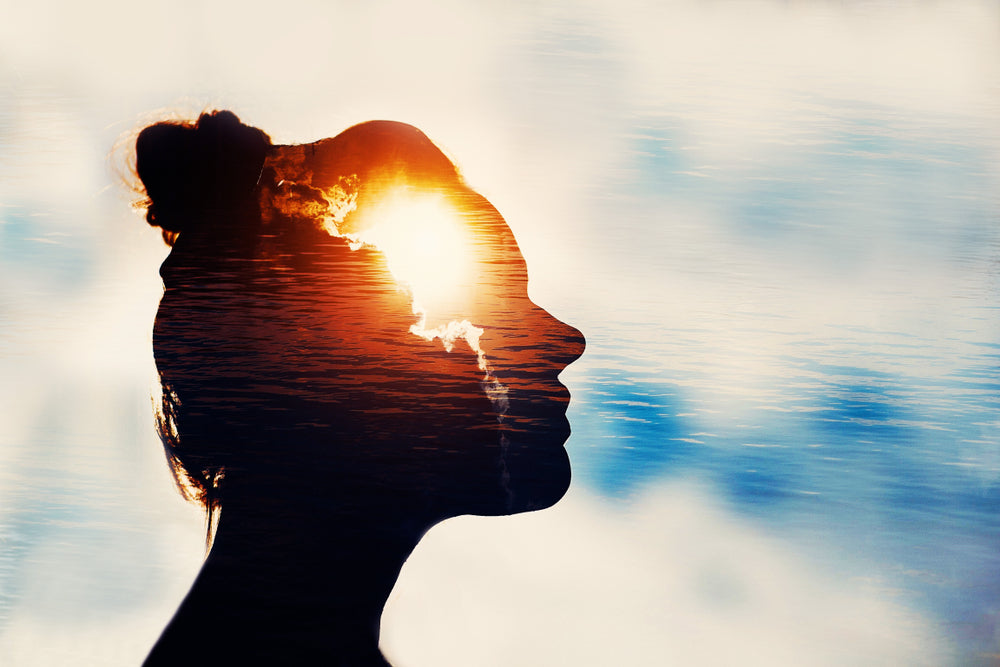 Womans-silhouette-on-sun-peeking-from-behind-clouds-on-clear-surface-of-water